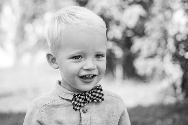 Tiene feliz. Día internacional de los niños. Adorable bebé divirtiéndose. Chico de traje y pajarita. Retrato de niño sonriente feliz en el fondo de la naturaleza . — Foto de Stock