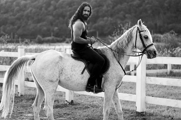 Homem sexy a cavalo. Jovem jóquei treinando seu cavalo para um passeio. Boa aparência, cowboy hunky monta cavalo na bela natureza do lado do país . — Fotografia de Stock