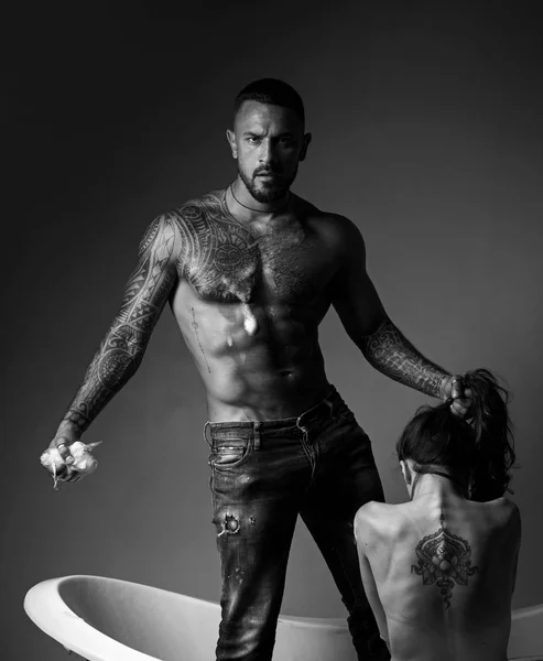 Dominant dans le jeu sexuel préliminaires. Couple tatoué. Homme et femme tatoués s'amusent dans la salle de bain et il lave son beau dos. Concept dominant . — Photo