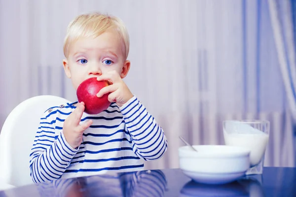 Babyvoeding. Eet gezond. Peuter neemt een snack. Gezonde voeding. Vitamine concept. Kind eet appel. Een leuke jongen zit aan tafel met bord en eten. Gezond eten. Jongen schattig baby eten ontbijt — Stockfoto