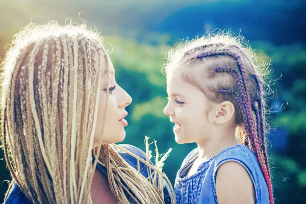 Мать и девочка играют и обнимаются. Заплетающиеся волосы. Милая девочка с косичками. Волосы в модном плетении. — стоковое фото