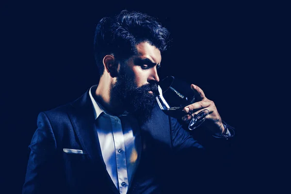 Radosny brodaty mężczyzna pije drogi koniak. Stary tradycyjny napój whisky - napój dla panów. Elegancki i stylowy mężczyzna w klasycznym, noszącym szkło z koniakiem w ręku. — Zdjęcie stockowe