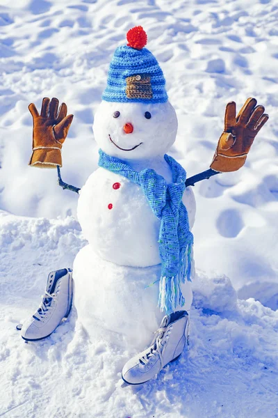 Cute little snowman outdoor. The snowman is wearing a fur hat and scarf. Snow man outdoor. Snowman isolated on snow background. Snowman in a scarf and hat.