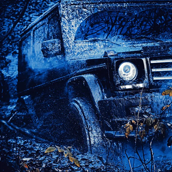 Vue du bas de la grande roue de voiture hors route sur route de campagne et fond de montagnes. Jeep s'est écrasé dans une flaque d'eau et a ramassé un jet de saleté. Expédition hors route. Véhicule tout-terrain va sur la montagne . — Photo