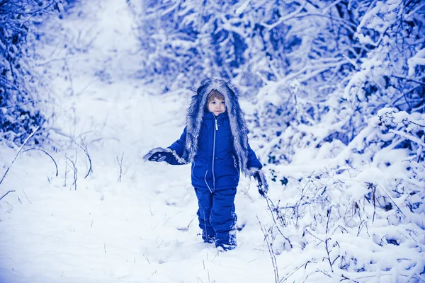 Ett litet barn på snöfältet. En liten pojke som går på vinterfältet. Pojken drömmer om vintern. Söt vinter pojke i frostig vinter Park. — Stockfoto