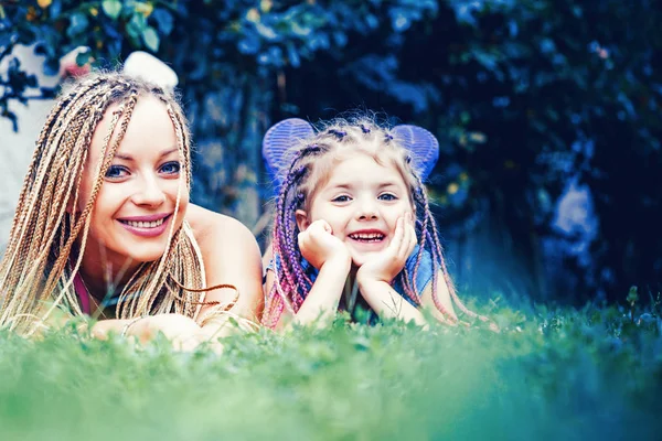 Мати і дочка насолоджуються зеленою травою і дивляться на камеру. Щаслива любляча сім'я - мати і дочка. Покоління сім'ї та концепція людей . — стокове фото
