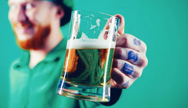 Porträtt av upphetsad man hålla glas öl på St Patricks day isolerad på grön. — Stockfoto
