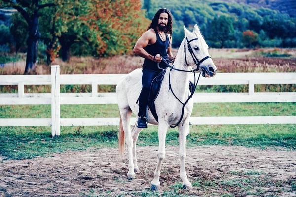 Cavalier sur cheval arabe gris dans le champ. Beau barbu qui monte à cheval à la ferme. Beau cheval avec cavalier homme trotter sur le terrain automnal. Concept d'amour équestre et animal. — Photo