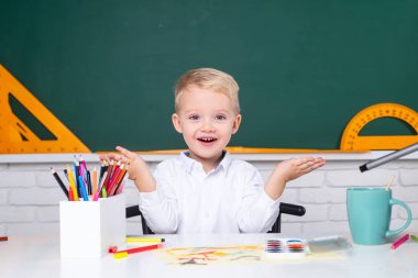 Sınıfta öğrenci portresi var. Öğrenciler için ev okulu. Evde eğitim. Okula dönelim. Okulda tahtaya yakın bir çocuk..