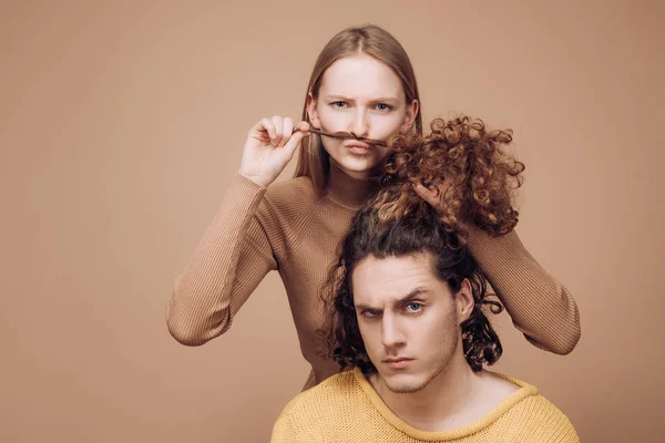 Différents types de concept de cheveux. Joyeux couple en photo studio amoureux. Bel homme aux cheveux longs ondulés et à sa mignonne petite amie. Belle fille jouant avec ses cheveux de petit ami . — Photo