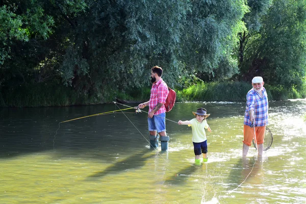 Nonno, padre e figlio pescano a mosca sul fiume. 3 uomini che pescano sul fiume in estate. Buon nonno e nipote stanno pescando sul fiume . — Foto Stock