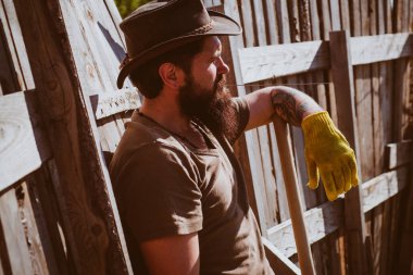 Şehir bahçesinde sakallı bahçıvan. Kırsal alan. Bahçıvanlık hobisi. Batı kovboy portresi.