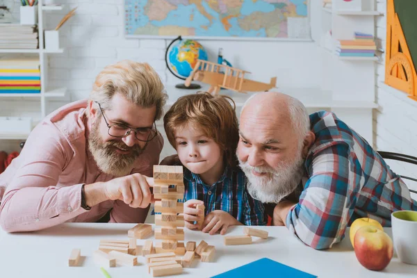リビングで遊ぶ3世代の現役男性。孫と孫が家で過ごす週末をリラックスして笑って. — ストック写真