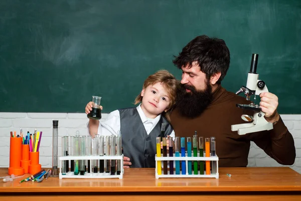 Учитель и ребенок. Учитель помогает своим подросткам с химией или биологией на занятиях по образованию. Учитель помогает ученикам учиться за партами в классе. Эксперимент — стоковое фото