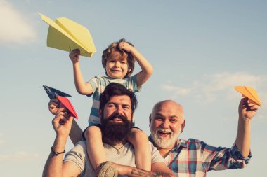 Dedemin oğlu ve torunu parkta eğleniyor. Mutlu bir aile. Büyükbaba oyun zamanı. Baba ve oğul mavi gökyüzünde oynuyorlar.