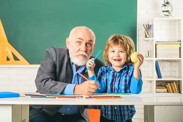 Portrait of happy grandfather and Son in classroom. Grandfather and grandchild - generation people concept. A grandfather and a son are learning in class. Back to school.