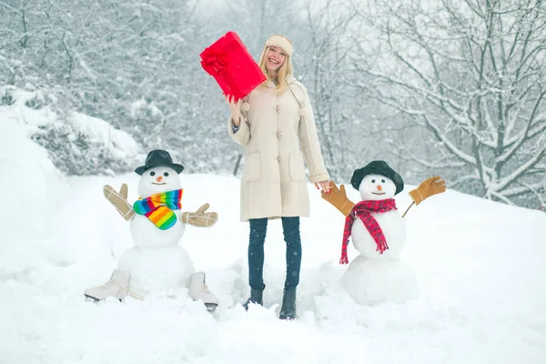 Fond d'hiver avec flocons de neige et bonhomme de neige. Fille jouant avec bonhomme de neige dans le parc d'hiver. Femme d'hiver . — Photo