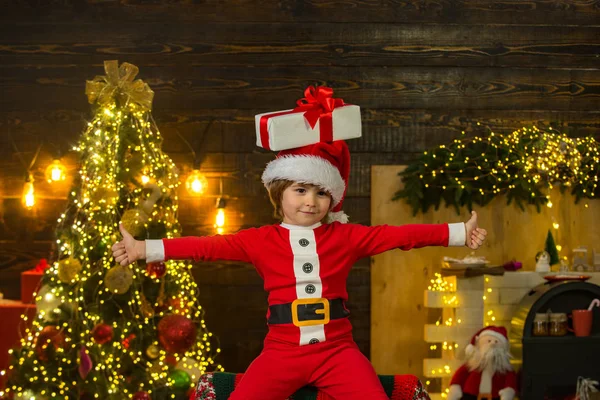 Barn njuter av semestern. Glad unge som har kul med gåvan. Julbarnet håller i en röd presentask. Julbarn - lycka koncept. — Stockfoto