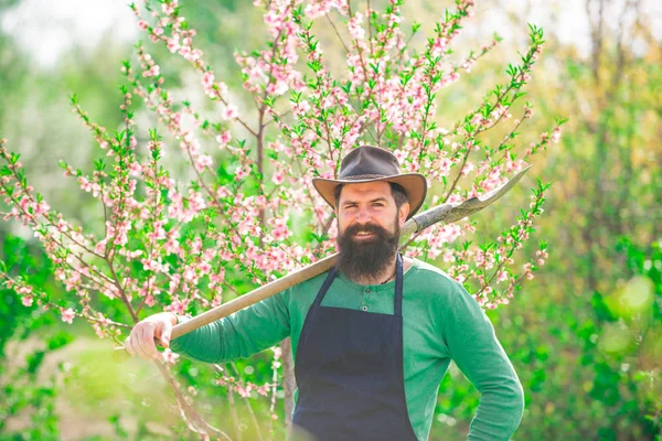 Landwirt arbeitet in einem Garten in der Nähe von Blumengarten. Porträt des Vaters bei der Arbeit im Garten. Öko-Bauernhof. Landwirt pflegt Pflanzen. — Stockfoto
