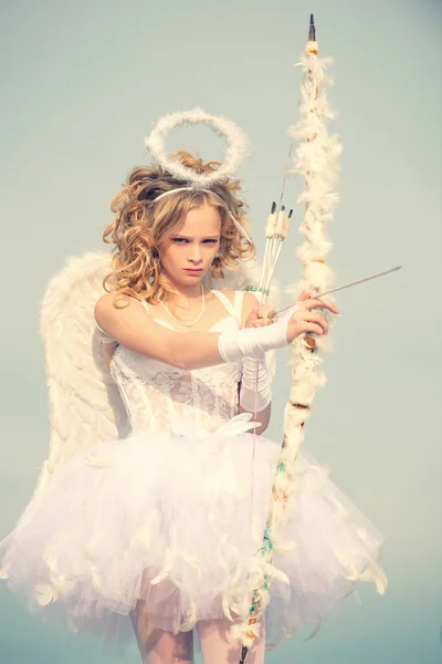 バレンタインデー。巻きブロンドの髪の天使の子供の女の子。白いドレスと翼のチャーミング巻きの女の子-天使のキューピッドの女の子。女の子天使とともにハローで白い天使のドレス — ストック写真