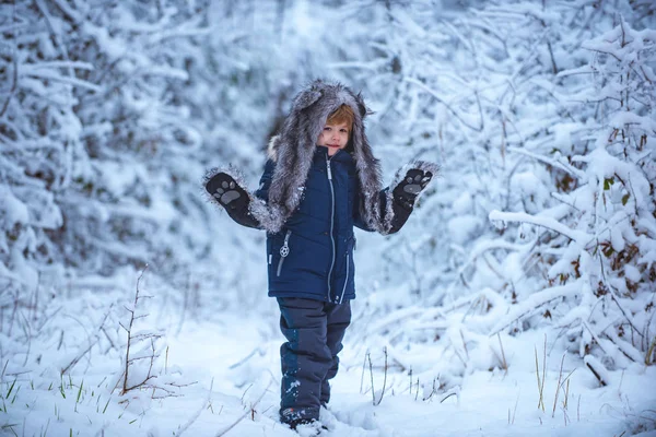 Zimní krajina lesa a sněhu s roztomilým chlapečkem. Děti se baví na bílém sněhovém poli proti zasněženým stromům. Lidé ve sněhu. — Stock fotografie