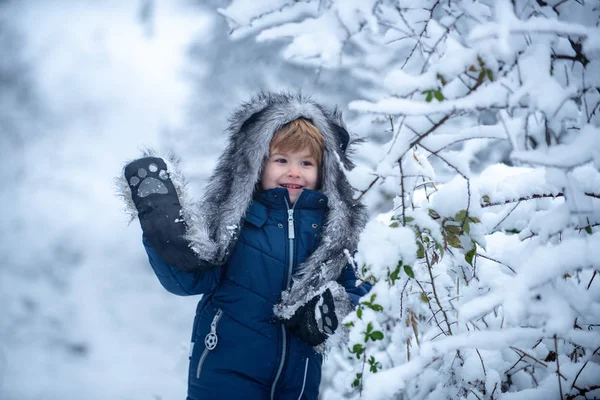 Barn leker på det snöiga fältet i vinterskogen. Glad vintertid. Vinterkläder för barn. Vinter barn fritid. — Stockfoto