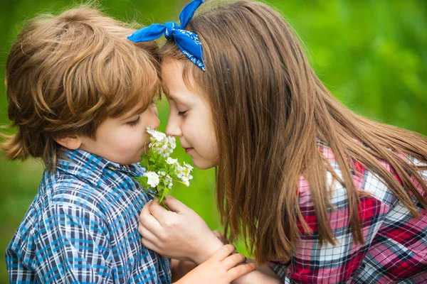 かわいい子供たちがタンポポを吹いている。タンポポの花を吹いて牧草地に座っている子供たちは幸せで遊び心があります. — ストック写真