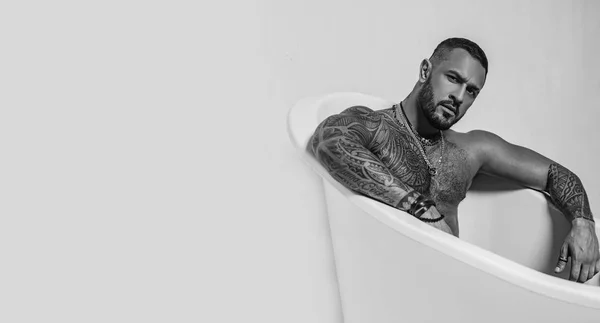 Spa et hygiène. temps de se détendre dans la salle de bain. le charisme de confiance. sportif brutal. stéroïdes. homme musclé avec corps athlétique. abdos sexy de tatoueur dans la baignoire. rester propre et frais. espace de copie — Photo