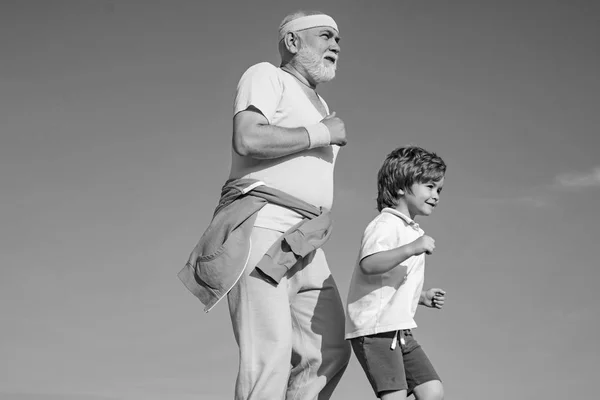 Joggen und Marathon laufen für die Familie. die alten und jungen Sportler, die auf der Straße laufen. Porträt eines gesunden Senior-Sportlers und eines sportlichen kleinen Jungen beim Joggen. Sommer und Aktivurlaub. — Stockfoto