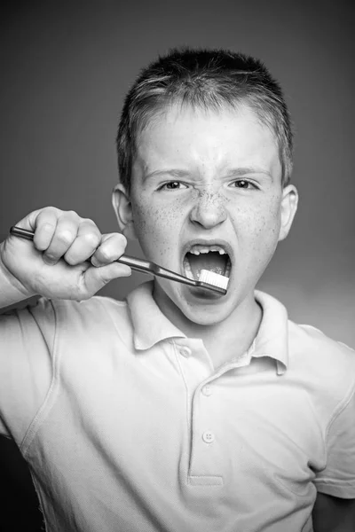 Cute funny boy with a toothbrush. Happy little boy brushing his teeth. Adorable little boy holding toothbrush and smiling at camera isolated on red. Dental hygiene. — Stock Photo, Image