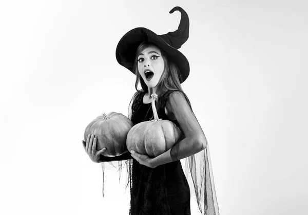 驚く女性。女性がかぼちゃのポーズします。魔女帽子と衣装のカボチャを保持している美しい若い驚く女性. — ストック写真