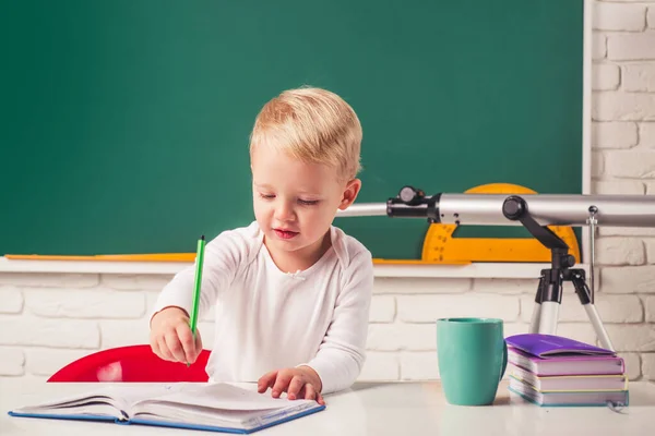 Leuke leerling met grappig gezichtsonderwijs werk. Portret van de leerling van de lagere school studie binnen. Onderwijsconcept voor kinderen. — Stockfoto