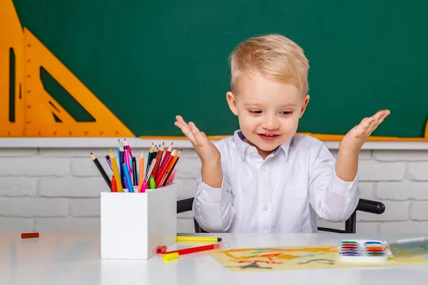 Mały uczeń zadowolony z doskonałego wyniku. Dzieciak uczy się w klasie na tle tablicy. Małe dzieci na lekcjach.. — Zdjęcie stockowe