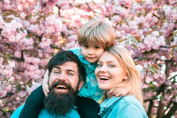 Çiçek açan bahçedeki mutlu aile portresi. Bahar geldi. Anne, baba ve oğul. — Stok fotoğraf