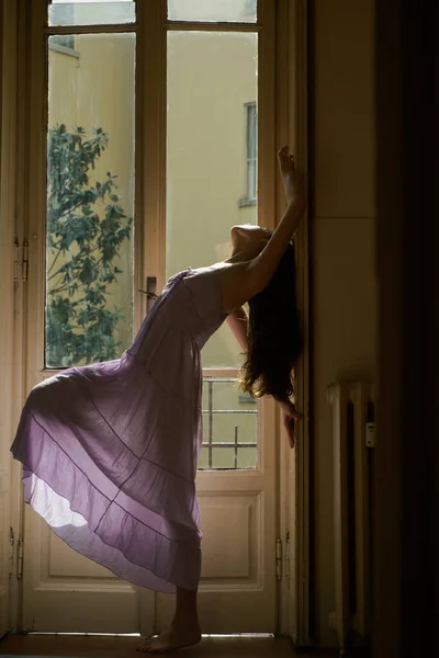 Sensual lady. She happy dances. Girl is dressed in nightwear. Young woman standing near balcony. Woman standing near the window after waking up with sunrise at morning.