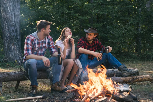 En grupp glada vänner som steker marshmallows på lägereld. Glada unga vänner som har picknick. Semester weekend picknick camping och vandring. Hitta sällskap för att resa och vandra. — Stockfoto