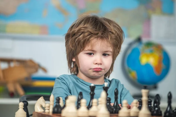 Kids early development. Concentrated little boy sitting at the table and playing chess. — Stock Photo, Image