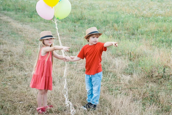 Šťastný pár - zábavný chlapeček a holčička na louce v létě v přírodě. Kluk se baví na venkově. — Stock fotografie
