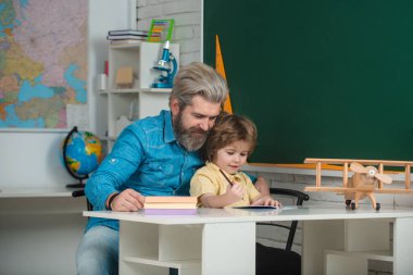 Baba oğluna öğretiyor. Genç, mutlu bir aile babası ve oğlu birlikte matematik okuyorlar. Derste mutlu okul çocukları.