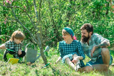 Biyolojik gıda üretim konsepti. Dünya günü. İşçi ailesi tarımı. Baharda bahçe işleri. Mutlu aile hasadı ve bol bol eğlence. Bahçede mutlu bir aile.