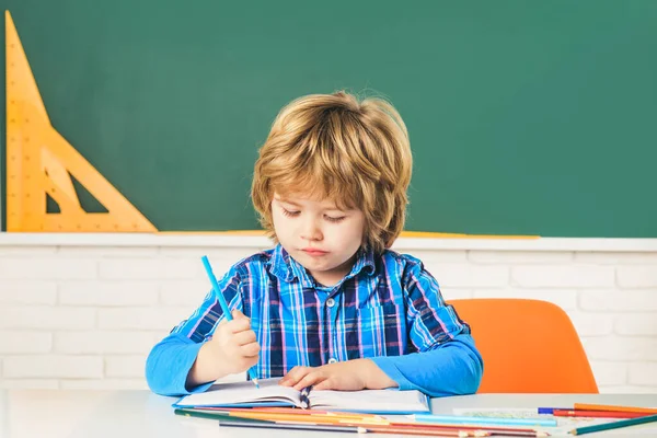 Child near chalkboard in school classroom. Happy school kids at lesson. Cute Preschool in Classroom.