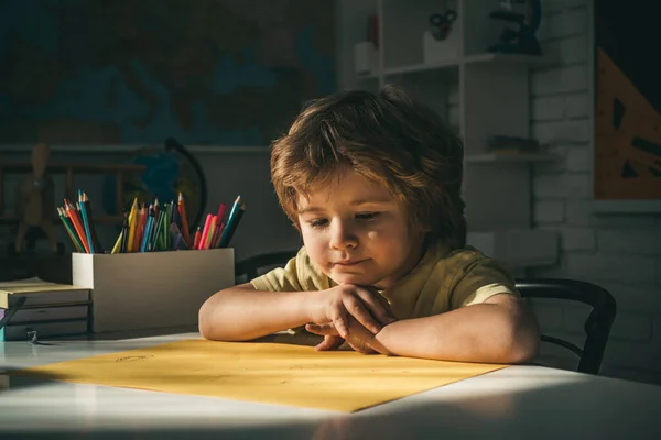 Aranyos tanuló, vicces arccal. Aranyos kisfiú az osztályteremben, közel a táblaasztalhoz. Boldog iskolás gyerekek az órán. — Stock Fotó