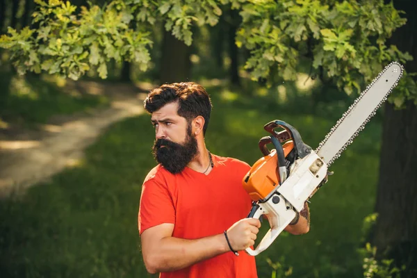 Deforestation. Man doing mans job. Lumberjack worker with chainsaw in the forest.