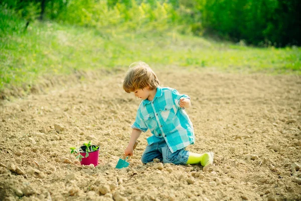 L'enfant passe du temps dans le verger. Jour de la Terre. Mignon petit garçon arrosant des fleurs dans le jardin de printemps. J'aime passer du temps à la ferme. . — Photo