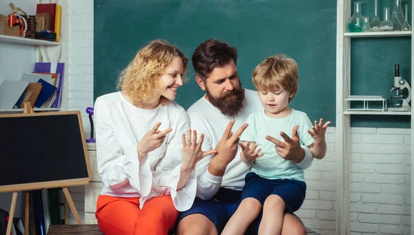 Scuola di famiglia. Piccolo bambino divertente con la famiglia che si diverte su sfondo lavagna. Concetto scolastico. I bambini si preparano per la scuola. Famiglia allegra giocare con set per la creatività . — Foto Stock