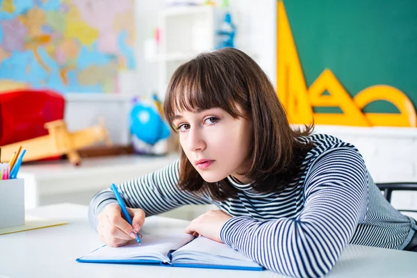 学習と教育の概念。女子学生。かわいいティーンエイジャーが家を描き、カメラを見ています。可愛いですティーネージャードローでカラフルなクレヨン. — ストック写真