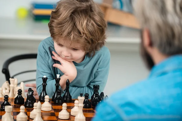 Vader leert zoon schaken. Begrip onderwijs en onderwijs. Leraar en kind. Knappe vader en zoon spelen schaak terwijl ze samen tijd doorbrengen.. — Stockfoto