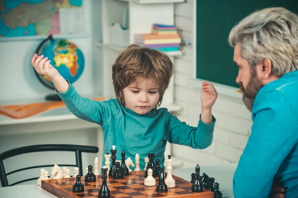 Vader leert zoon schaken. Gelukkige twee generaties mannen hebben plezier en schaken. Slim geconcentreerd en denkend kind tijdens het schaken. Vroegtijdige ontwikkeling van kinderen. — Stockfoto