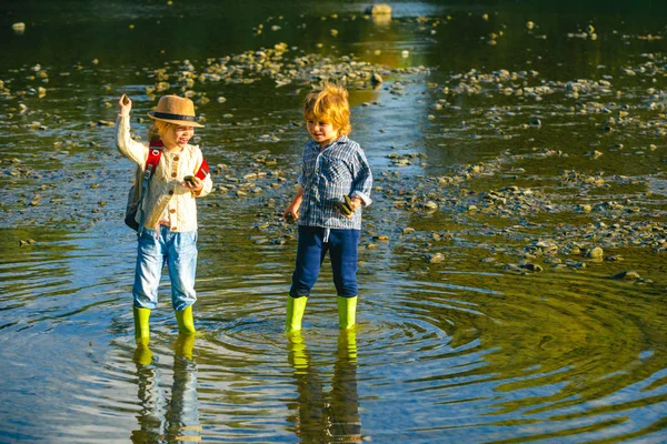 Les enfants jettent des pierres à la rivière Stony. De beaux enfants jettent un rocher sur la rivière. Sauter des rochers. — Photo