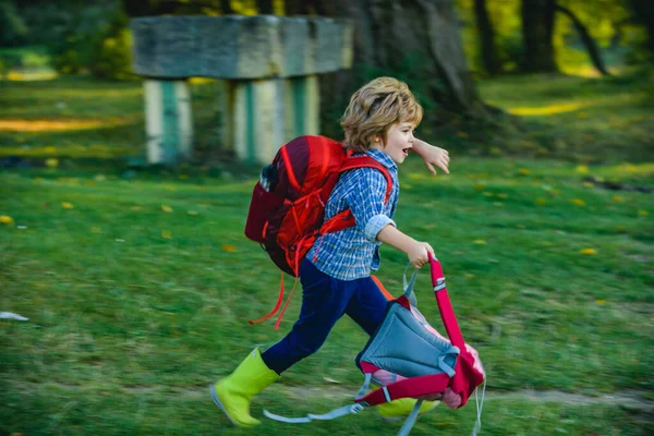 Crianças correndo no campo verde no fundo verde Menino com mochila de caminhantes viajando no acampamento. Criança carregando aventura mochila na floresta com viagem escolar. Sonhos e viagens . — Fotografia de Stock